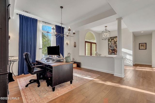 home office featuring a notable chandelier, a healthy amount of sunlight, and ornate columns