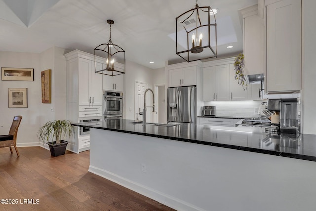 kitchen featuring white cabinetry, sink, a chandelier, hanging light fixtures, and stainless steel appliances