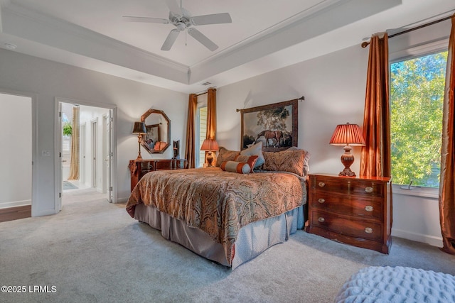 bedroom with crown molding, ceiling fan, ensuite bathroom, light carpet, and a raised ceiling