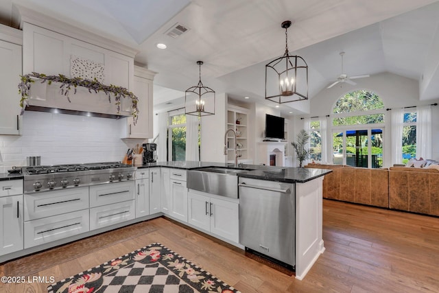 kitchen with appliances with stainless steel finishes, pendant lighting, tasteful backsplash, white cabinetry, and lofted ceiling