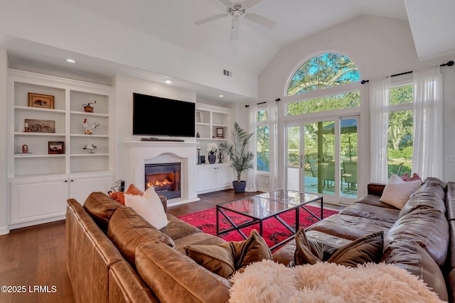 living room with built in shelves, ceiling fan, lofted ceiling, and dark hardwood / wood-style floors