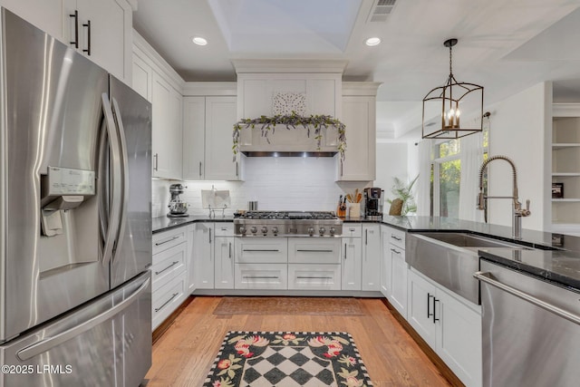 kitchen with hanging light fixtures, white cabinetry, appliances with stainless steel finishes, and sink