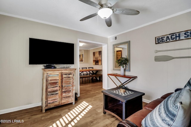 living room featuring hardwood / wood-style floors, crown molding, and ceiling fan