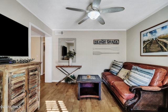 living room with ornamental molding, light hardwood / wood-style floors, and ceiling fan