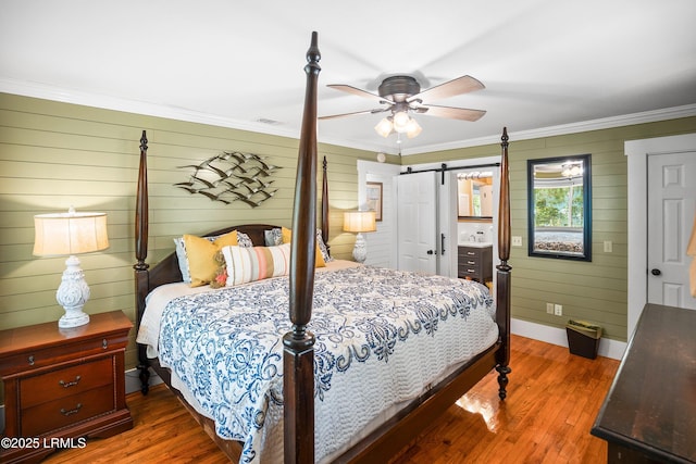 738 Marlin Dr, Fripp Island, SC 29920 - bedroom featuring hardwood / wood-style flooring, ornamental molding, baseboards, wooden walls, and a barn door