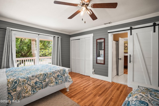 738 Marlin Dr, Fripp Island, SC 29920 - bedroom featuring crown molding, a barn door, wood finished floors, a ceiling fan, and wooden walls