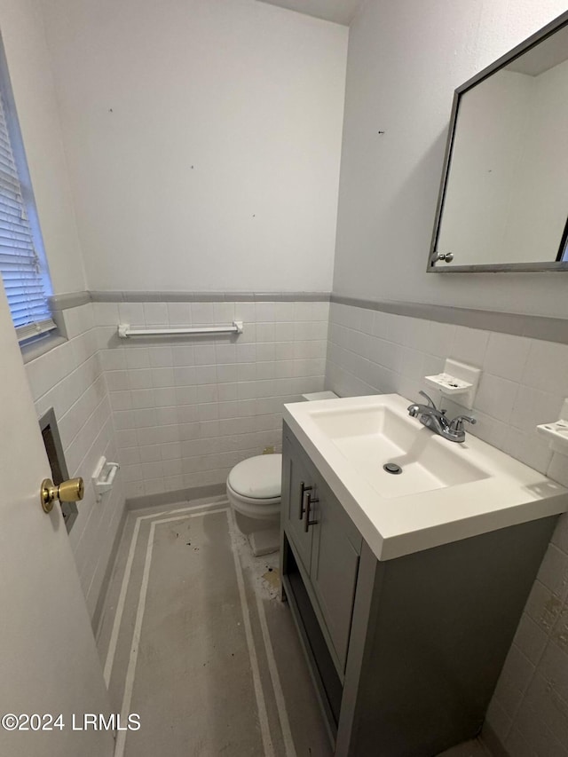 bathroom with vanity, toilet, and tile walls