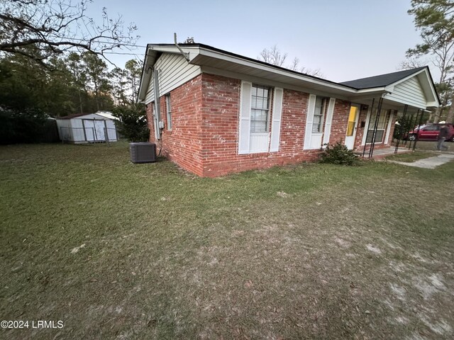 view of home's exterior with cooling unit, covered porch, a shed, and a lawn