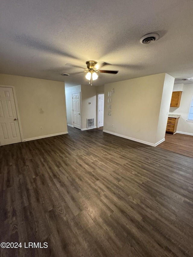 unfurnished living room featuring dark hardwood / wood-style flooring, ceiling fan, and a textured ceiling