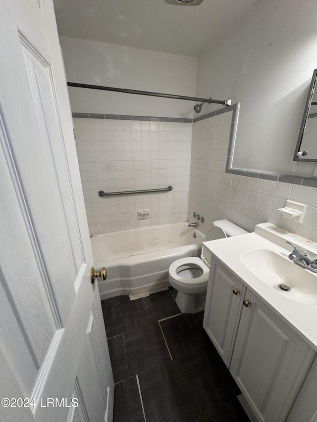 full bathroom with tile walls, vanity, tiled shower / bath combo, and toilet