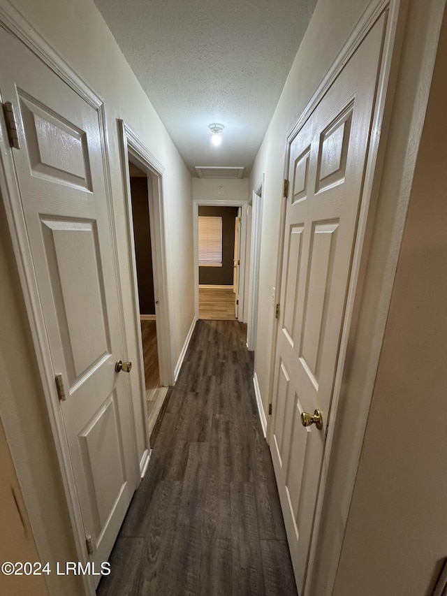 hallway featuring dark hardwood / wood-style flooring and a textured ceiling