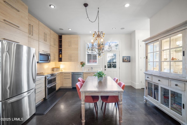 kitchen with sink, stainless steel appliances, light brown cabinetry, decorative light fixtures, and a chandelier