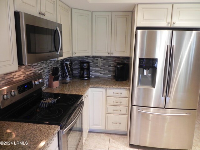 kitchen featuring backsplash, stainless steel appliances, white cabinets, and stone countertops