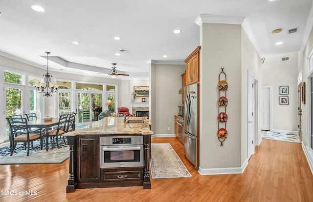 kitchen with sink, hanging light fixtures, ornamental molding, stainless steel appliances, and light stone countertops