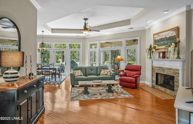 sunroom featuring an inviting chandelier, a tray ceiling, and a stone fireplace