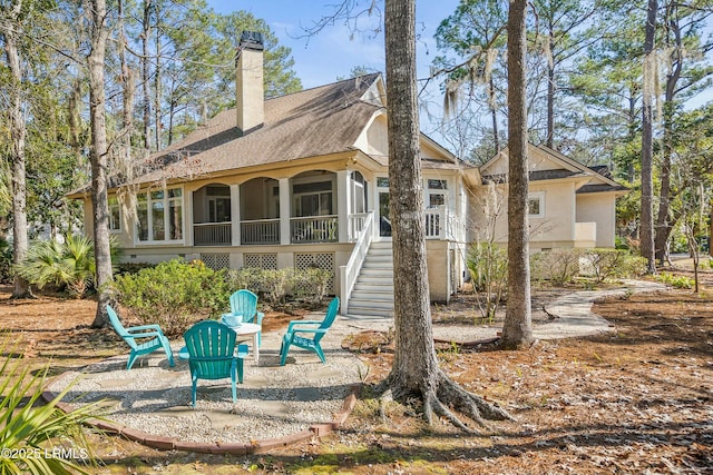 64 Osprey Cir, Okatie, SC 29909 - back of property with a chimney, a sunroom, stairs, roof with shingles, and stucco siding