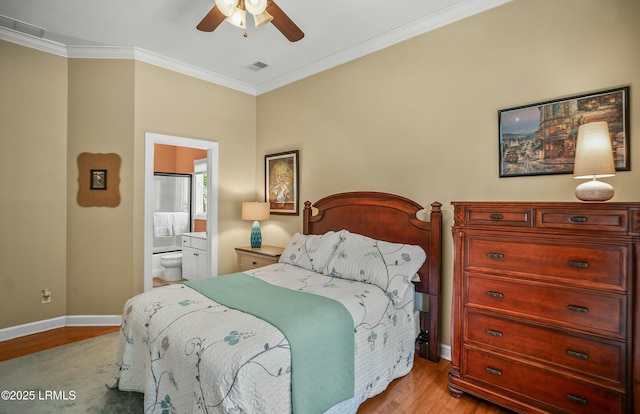 bedroom featuring ornamental molding, ensuite bathroom, ceiling fan, and light wood-type flooring