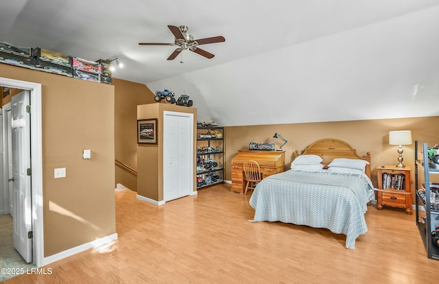 bedroom featuring ceiling fan, lofted ceiling, a closet, and light wood-type flooring