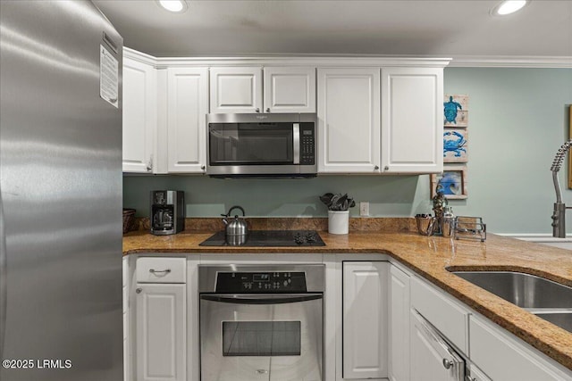 kitchen with recessed lighting, a sink, white cabinets, ornamental molding, and appliances with stainless steel finishes