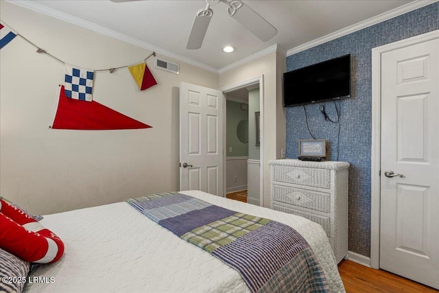 bedroom featuring ceiling fan, ornamental molding, wood finished floors, and visible vents