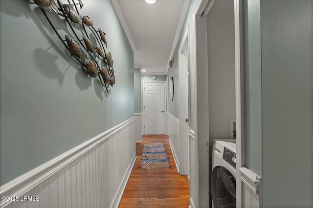 hall with a wainscoted wall, washer / clothes dryer, wood finished floors, and ornamental molding