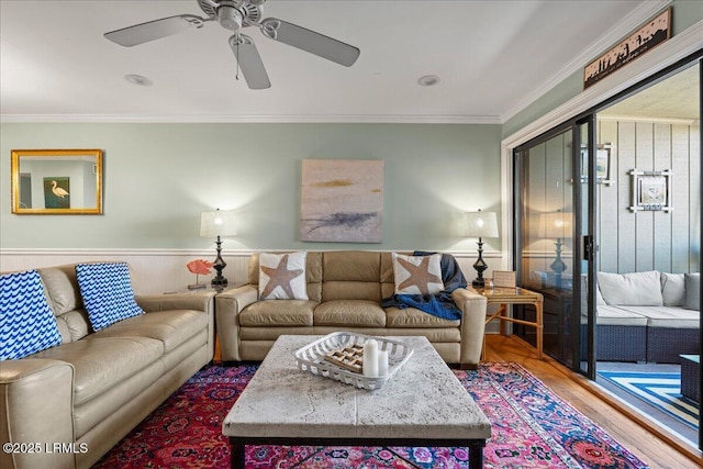 living room featuring a ceiling fan, crown molding, and wood finished floors