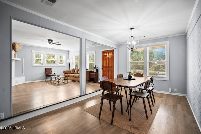 dining room featuring wood finished floors, a chandelier, crown molding, baseboards, and ceiling fan