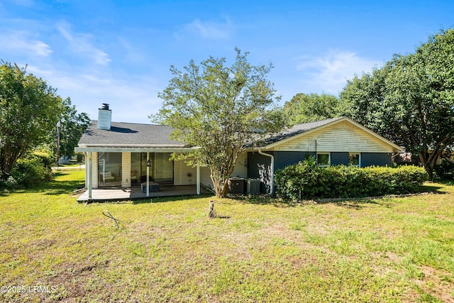 back of property with a yard, a chimney, and a patio area
