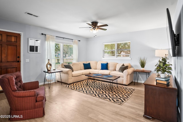living area with a ceiling fan, light wood-style flooring, and baseboards