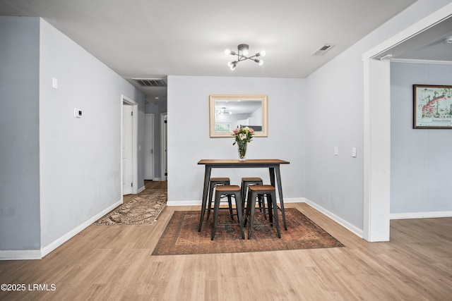 dining space featuring wood finished floors, baseboards, and a chandelier
