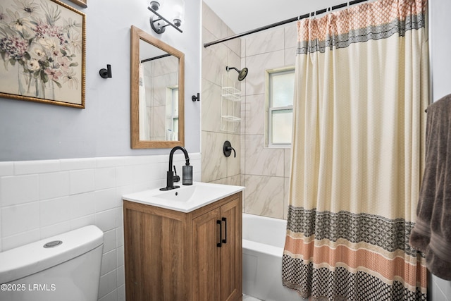 full bathroom featuring tile walls, shower / bath combo with shower curtain, toilet, vanity, and a wainscoted wall