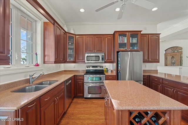 kitchen featuring sink, light hardwood / wood-style flooring, stainless steel appliances, a center island, and ornamental molding