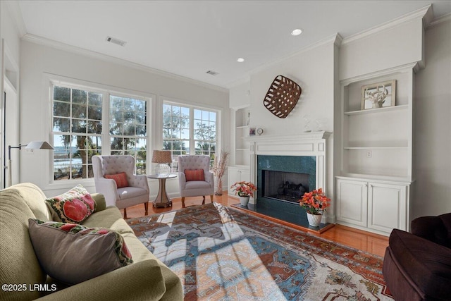 living room with hardwood / wood-style flooring, a premium fireplace, ornamental molding, and built in shelves