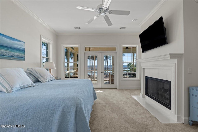 bedroom featuring french doors, crown molding, a tile fireplace, light colored carpet, and access to exterior