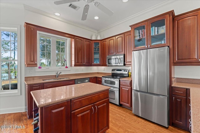 kitchen with light stone counters, ornamental molding, appliances with stainless steel finishes, and sink