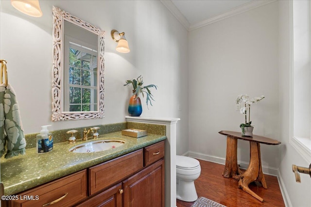 bathroom featuring vanity, hardwood / wood-style floors, ornamental molding, and toilet