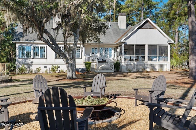 rear view of house with a yard, a fire pit, and a sunroom