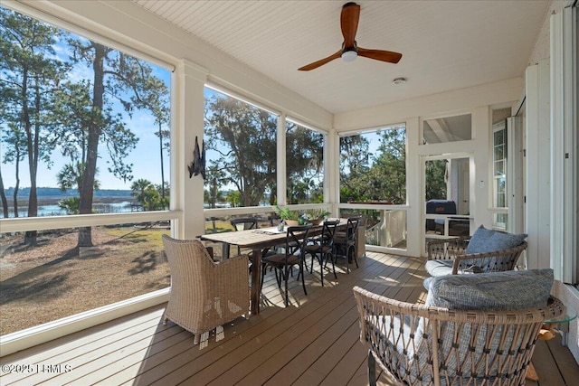 sunroom featuring ceiling fan and a water view