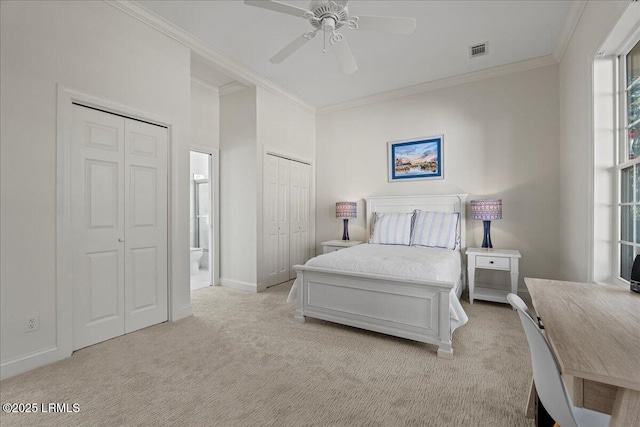 bedroom featuring crown molding, ceiling fan, connected bathroom, light colored carpet, and multiple closets