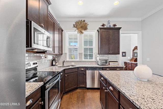 2712 Bluestem Dr, Beaufort, SC 29902 - kitchen with stainless steel appliances, dark brown cabinets, ornamental molding, a sink, and decorative backsplash