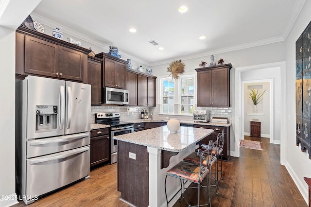 2712 Bluestem Dr, Beaufort, SC 29902 - kitchen featuring stainless steel appliances, backsplash, a center island, dark brown cabinetry, and a kitchen bar