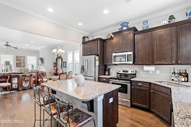 2712 Bluestem Dr, Beaufort, SC 29902 - kitchen featuring open floor plan, dark brown cabinetry, appliances with stainless steel finishes, light stone counters, and a breakfast bar area