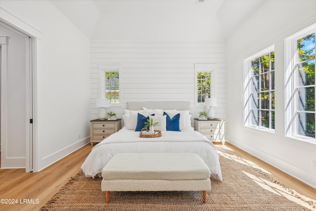 bedroom with lofted ceiling, hardwood / wood-style floors, and wood walls