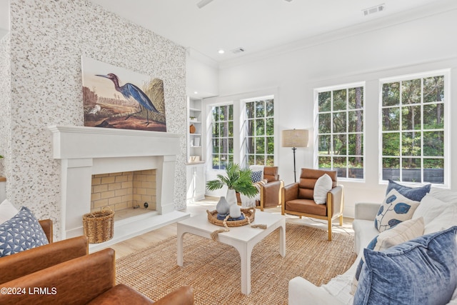 living room featuring crown molding, a large fireplace, plenty of natural light, and wood-type flooring