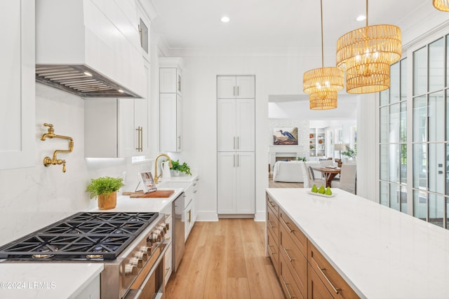 kitchen featuring premium range hood, an inviting chandelier, decorative light fixtures, light stone countertops, and white cabinets