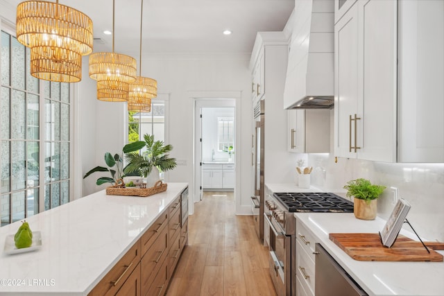 kitchen with premium range hood, white cabinetry, hanging light fixtures, stainless steel stove, and light stone countertops