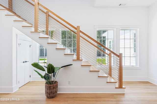 stairway with plenty of natural light and wood-type flooring