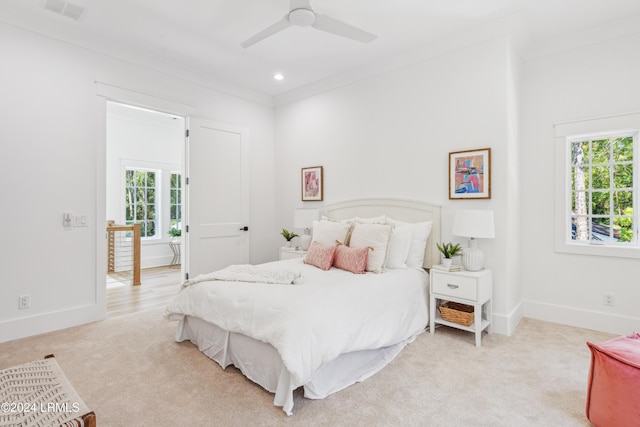 bedroom with multiple windows, crown molding, light carpet, and ceiling fan