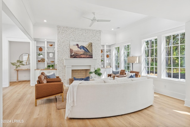 living room featuring built in shelves, a fireplace, and light wood-type flooring