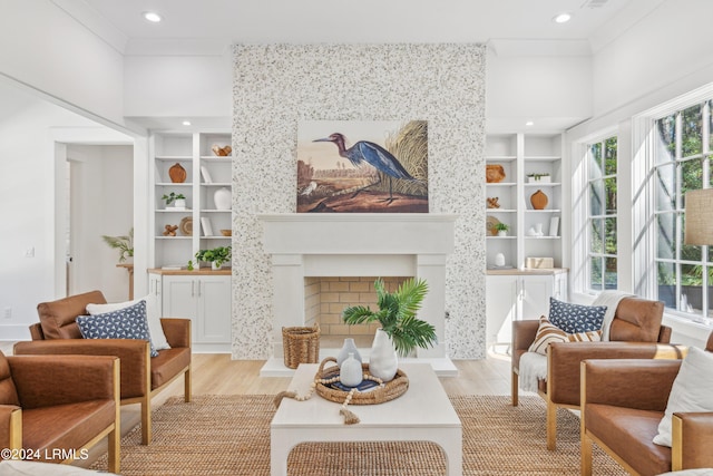 living area with built in shelves, ornamental molding, and light wood-type flooring